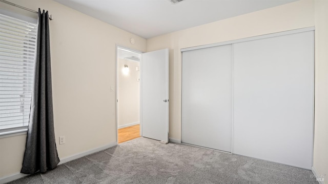 unfurnished bedroom with a closet and light colored carpet