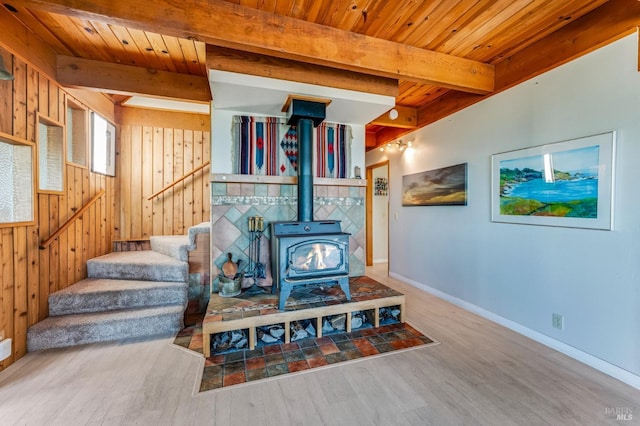 sitting room featuring hardwood / wood-style floors, beamed ceiling, a wood stove, wood walls, and wooden ceiling