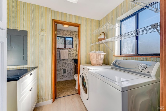 washroom featuring electric panel, light hardwood / wood-style floors, and washing machine and clothes dryer