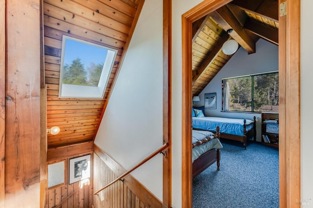 interior space featuring carpet floors, vaulted ceiling with skylight, wood ceiling, and wooden walls