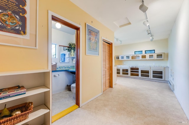 hallway with track lighting, light colored carpet, and a baseboard radiator