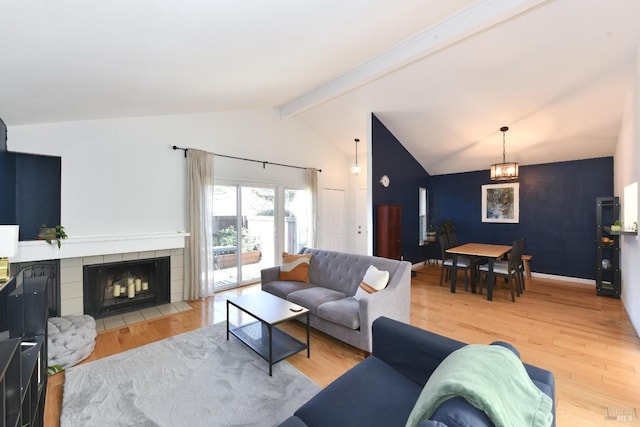 living room with lofted ceiling with beams, a tile fireplace, and wood-type flooring