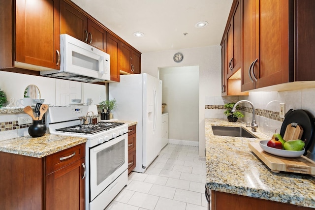 kitchen featuring backsplash, light stone counters, sink, and white appliances