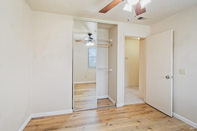 unfurnished bedroom featuring ceiling fan, a closet, and hardwood / wood-style flooring