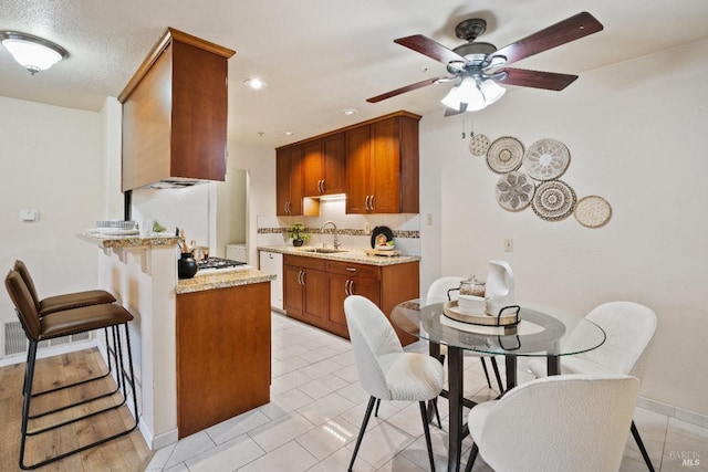 kitchen featuring ceiling fan, light tile patterned flooring, dishwasher, light stone counters, and sink