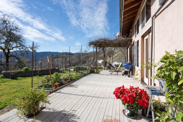 deck featuring a mountain view, a yard, and grilling area