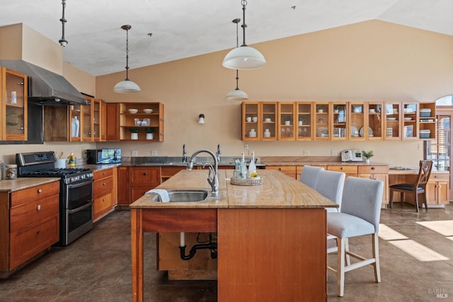 kitchen featuring a breakfast bar, decorative light fixtures, vaulted ceiling, a kitchen island with sink, and range with two ovens