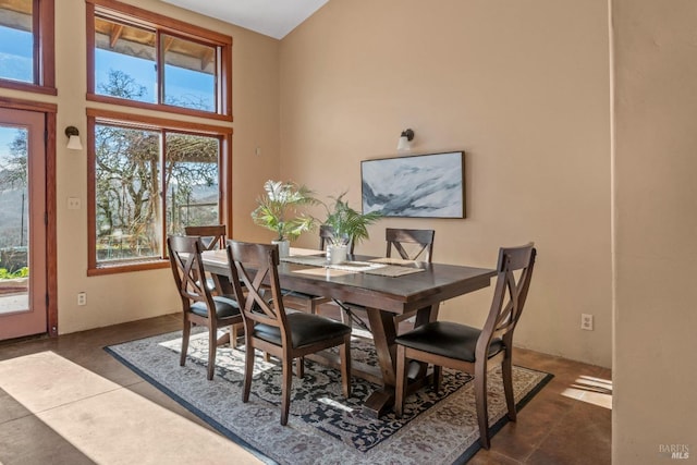 dining area featuring a high ceiling and dark tile patterned flooring