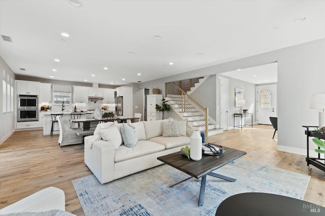 living room featuring sink and light hardwood / wood-style flooring