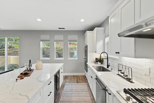 kitchen with sink, white cabinetry, tasteful backsplash, light stone counters, and appliances with stainless steel finishes