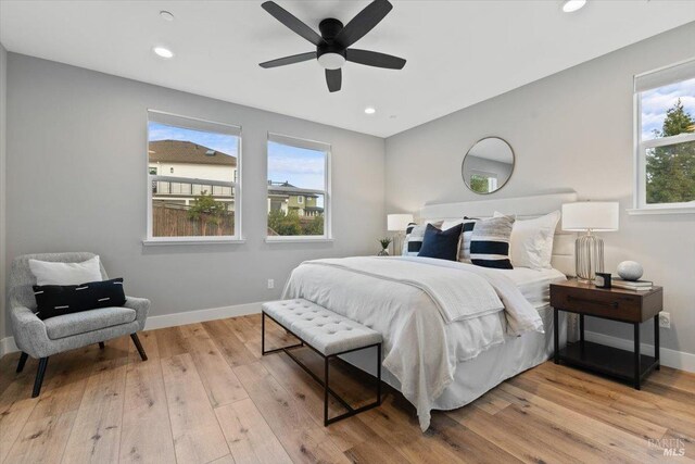 bedroom featuring multiple windows, light hardwood / wood-style floors, and ceiling fan