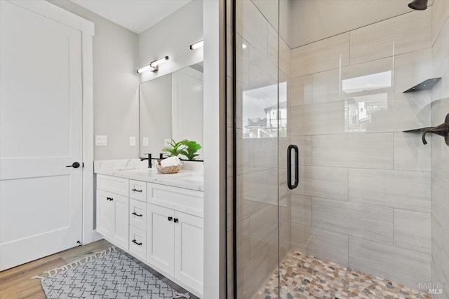 bathroom with vanity, hardwood / wood-style floors, and a shower with door