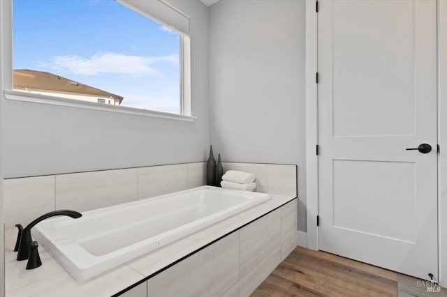 bathroom with hardwood / wood-style flooring and tiled bath