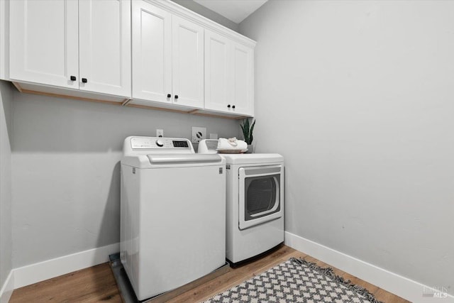 laundry area with cabinets, washer and clothes dryer, and light hardwood / wood-style flooring