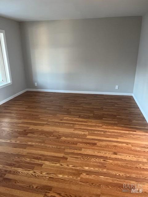 empty room featuring baseboards and dark wood-type flooring