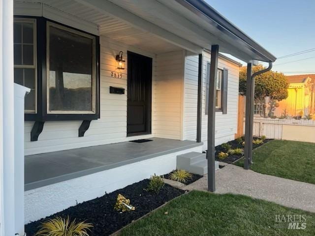 property entrance featuring a lawn and a porch