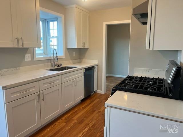 kitchen featuring a sink, under cabinet range hood, dishwashing machine, white cabinets, and wood finished floors