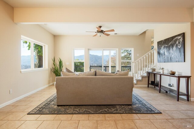 tiled living room featuring a mountain view, beam ceiling, and ceiling fan