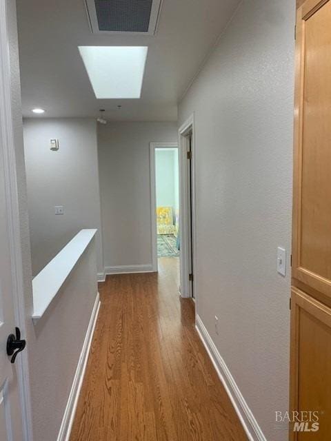 hall featuring a skylight and light hardwood / wood-style floors