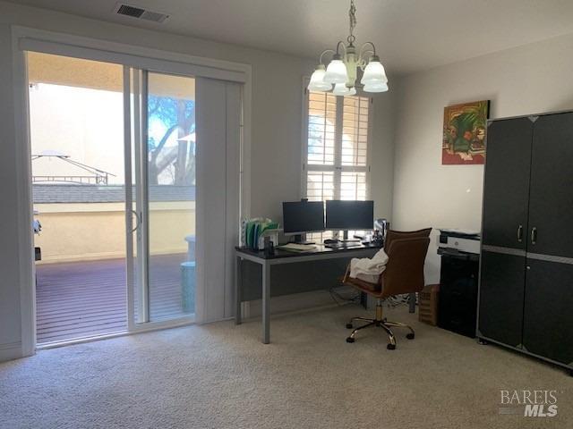 carpeted home office featuring a notable chandelier