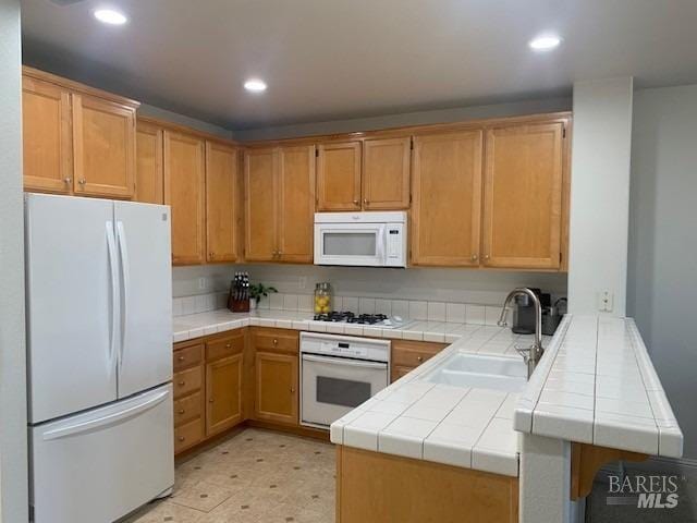 kitchen featuring tile countertops, sink, kitchen peninsula, and white appliances