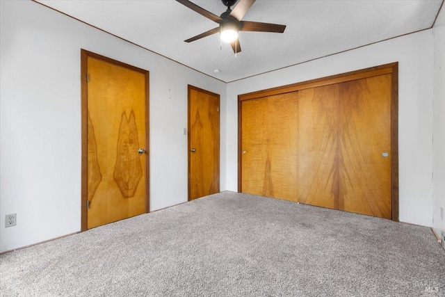 unfurnished bedroom with ceiling fan, carpet, and a closet