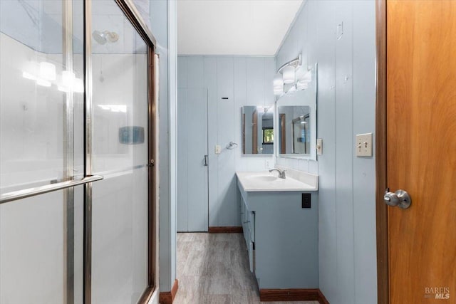 bathroom featuring wood-type flooring, walk in shower, vanity, and wood walls