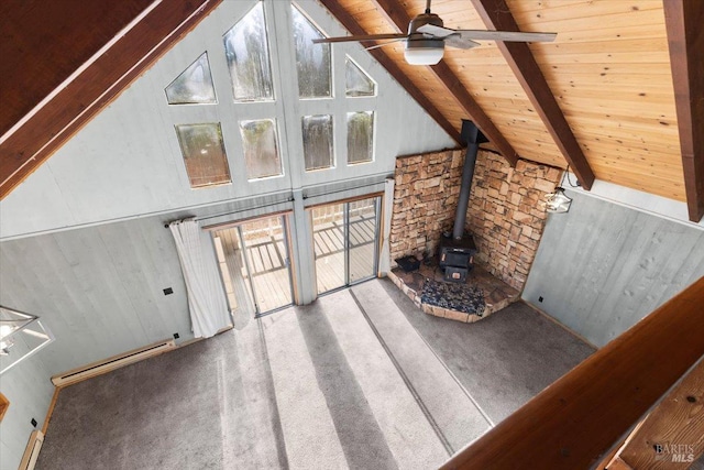 unfurnished living room featuring high vaulted ceiling, beamed ceiling, wood ceiling, a wood stove, and light carpet