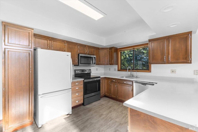 kitchen featuring appliances with stainless steel finishes, a tray ceiling, and sink