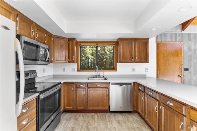 kitchen with light hardwood / wood-style floors, sink, a tray ceiling, and stainless steel appliances