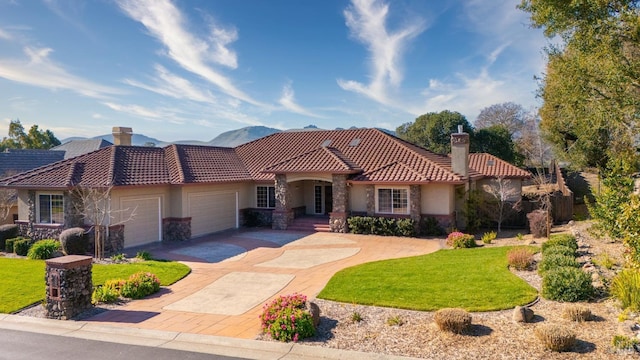 mediterranean / spanish-style home featuring a mountain view, a garage, and a front yard