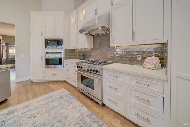 kitchen featuring backsplash, white cabinetry, light wood-type flooring, and appliances with stainless steel finishes