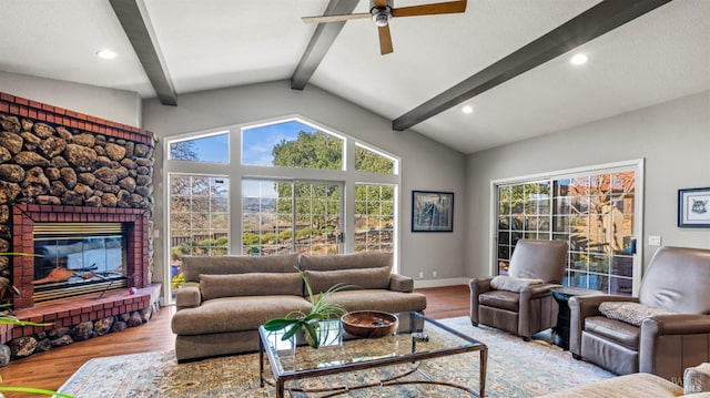 living room with light wood-type flooring, ceiling fan, vaulted ceiling with beams, and a fireplace