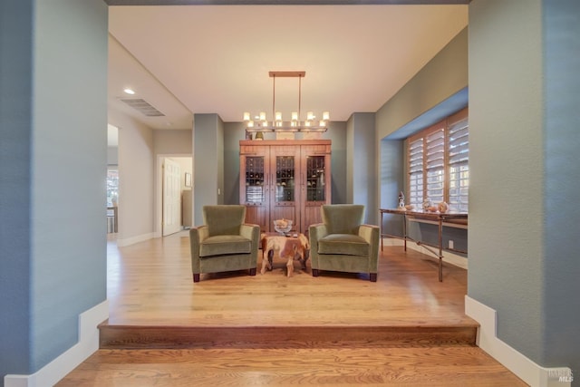 sitting room with wood-type flooring and a notable chandelier