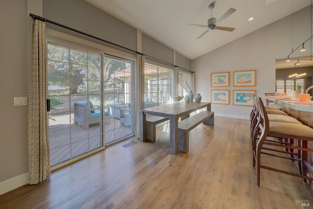 dining space featuring ceiling fan with notable chandelier, hardwood / wood-style floors, and vaulted ceiling