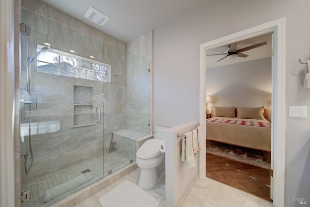 bathroom featuring toilet, ceiling fan, a shower with door, and tile patterned flooring