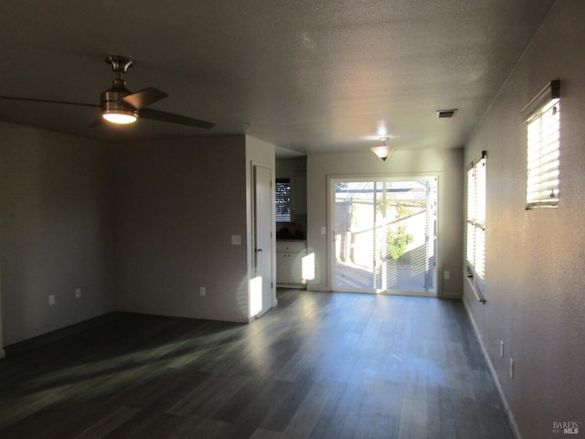 spare room with a textured ceiling, dark wood-type flooring, and ceiling fan