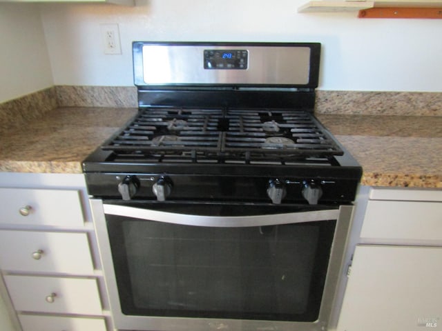 room details with white cabinets and gas stove