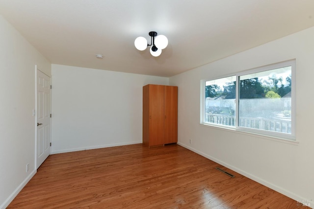 unfurnished room with a chandelier and hardwood / wood-style floors