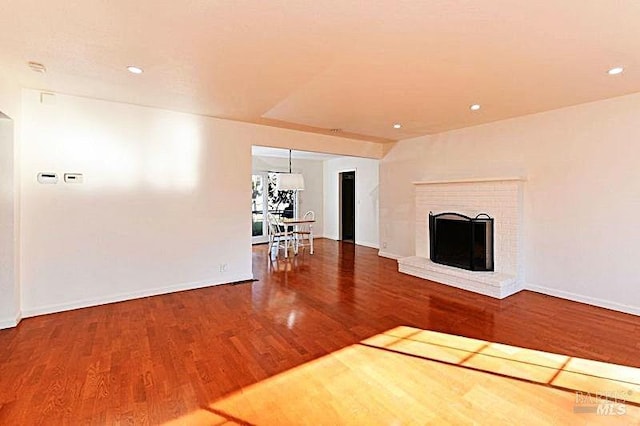 unfurnished living room featuring a brick fireplace and hardwood / wood-style floors