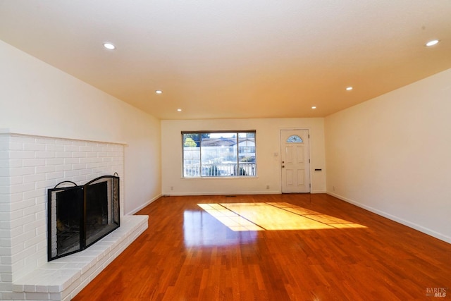 unfurnished living room with hardwood / wood-style flooring and a brick fireplace