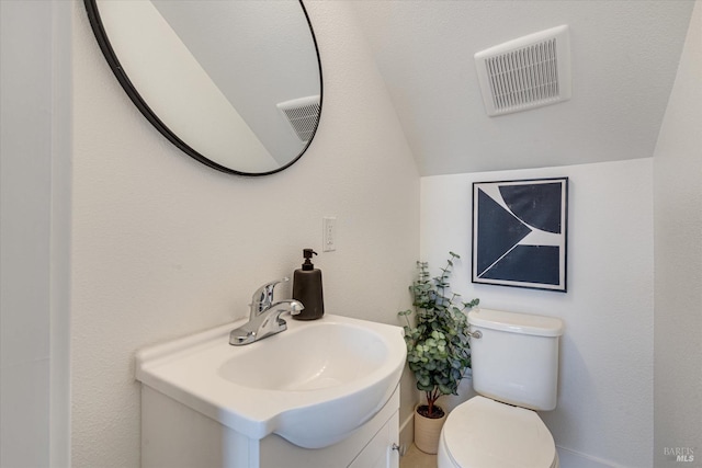 bathroom featuring toilet, vanity, and lofted ceiling