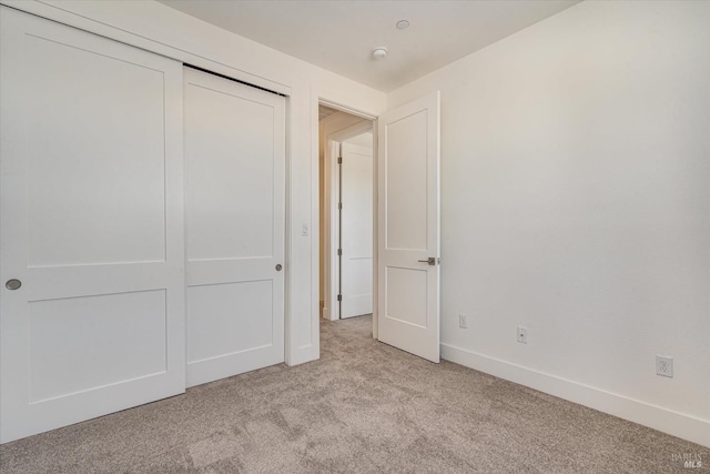 unfurnished bedroom with light carpet and a closet