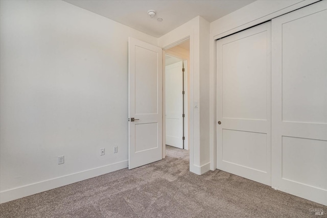 unfurnished bedroom with light carpet and a closet