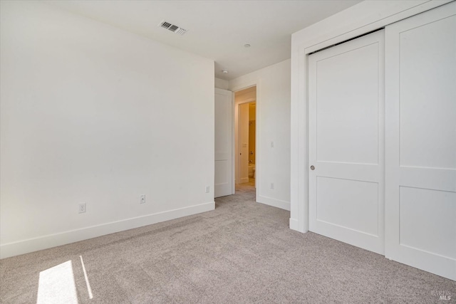 unfurnished bedroom featuring light colored carpet and a closet