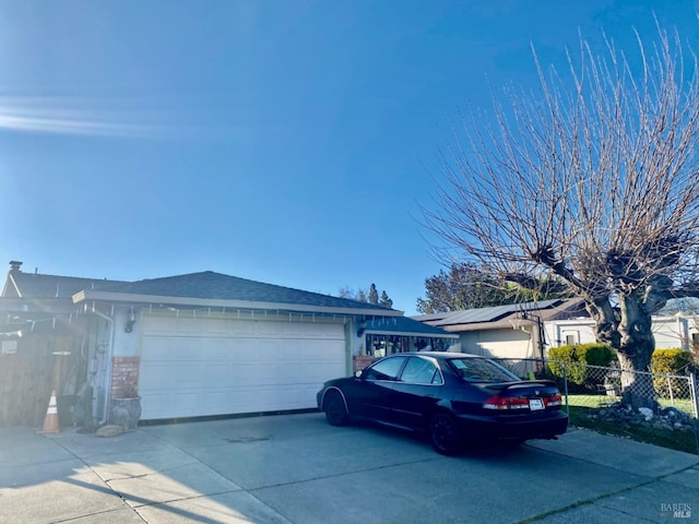 view of property exterior with concrete driveway, an attached garage, fence, and stone siding