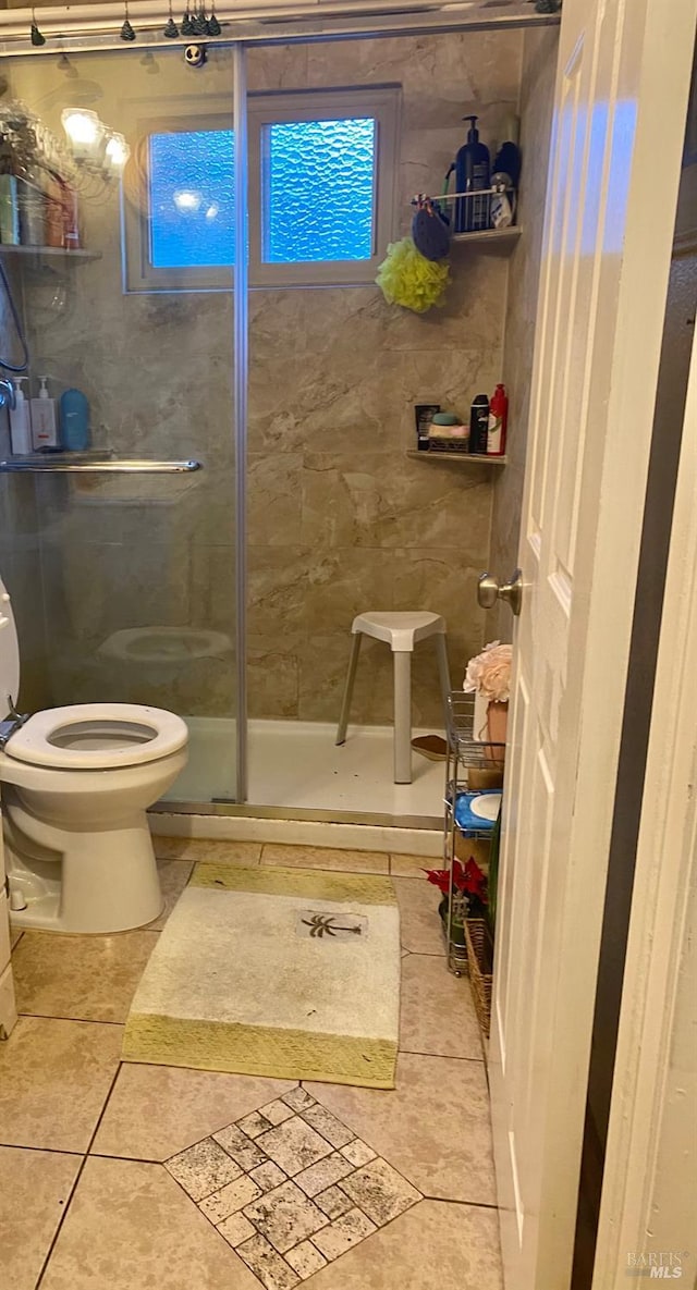 bathroom with toilet, a stall shower, and tile patterned floors