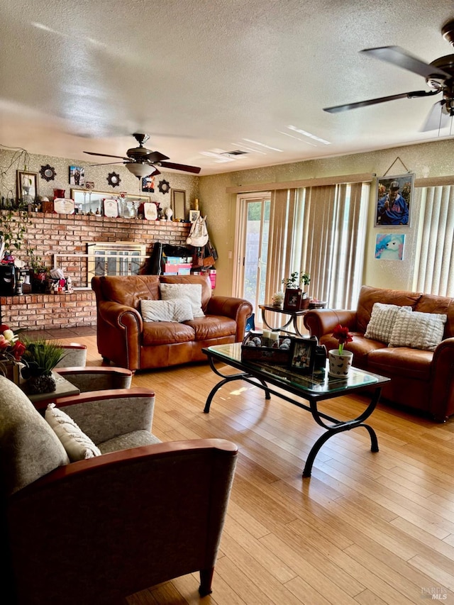 living room with a ceiling fan, a textured ceiling, and light wood-type flooring