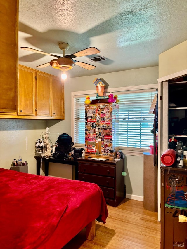 bedroom featuring baseboards, a ceiling fan, a textured ceiling, and light wood-style flooring