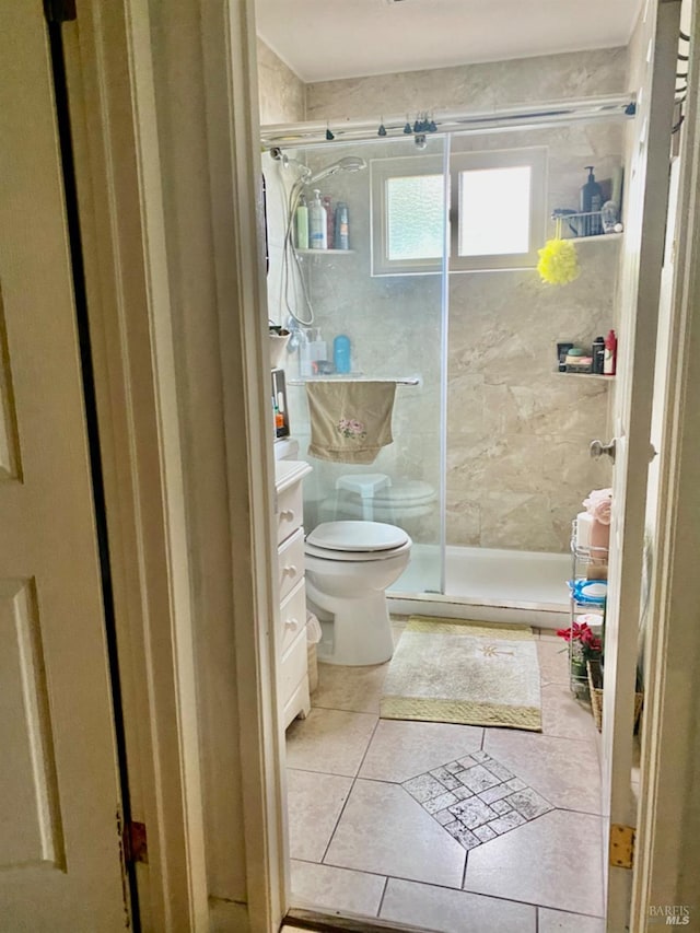 bathroom featuring toilet, a stall shower, vanity, and tile patterned flooring